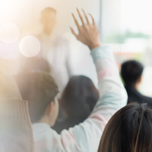 Mental Health First Aid Workshop with participants raising hands in a classroom setting