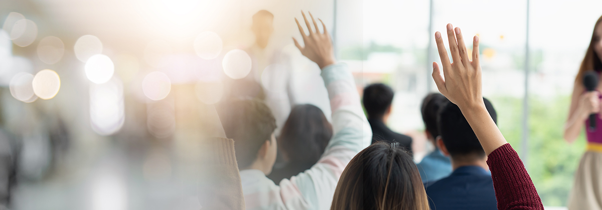 Mental Health First Aid Workshop with participants raising hands in a classroom setting